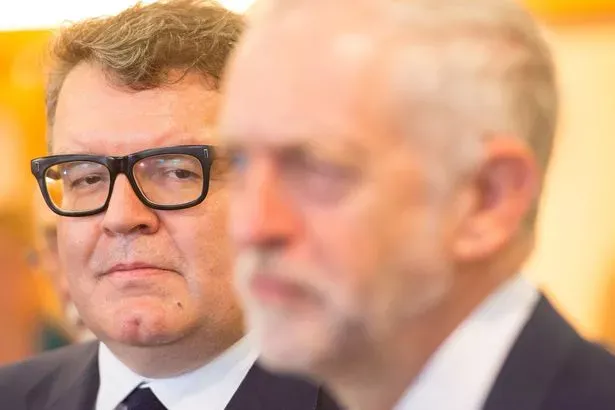 Tom Watson watching Jeremy Corbyn speak.