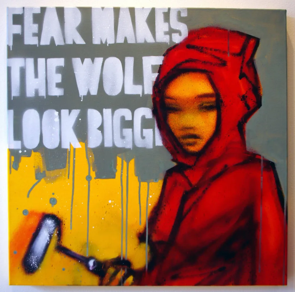 POC in a red hoodie adding graffiti to a wall that says "fear makes the wolf look bigger"